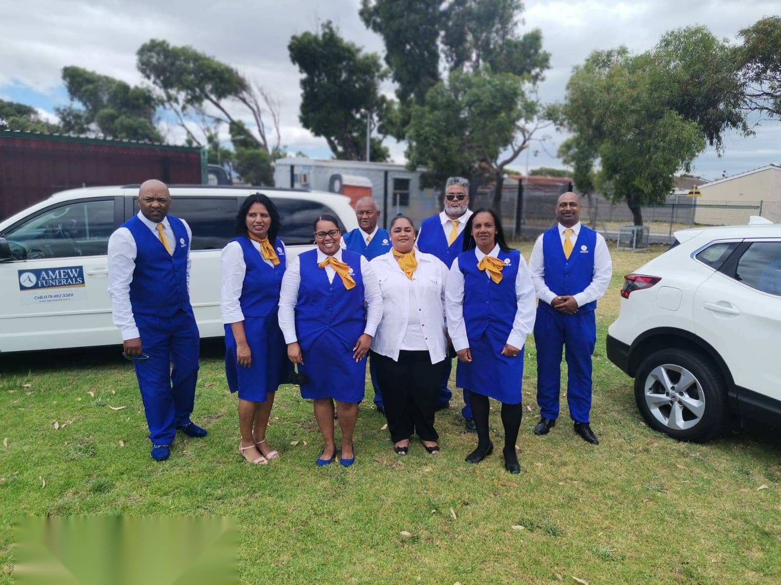 The AMEW team in uniform in front of an AMEW Funerals vehicle